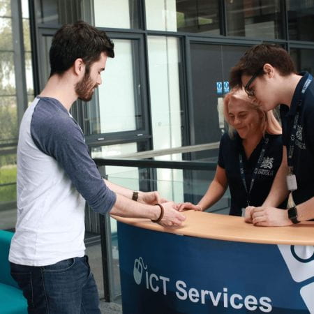 Two ICT student staff members on the roadshow stand assisting a user.